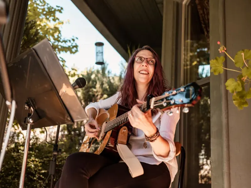 Musical notes flow from connected front porches, symbolizing free neighborhood concerts across the U.S.