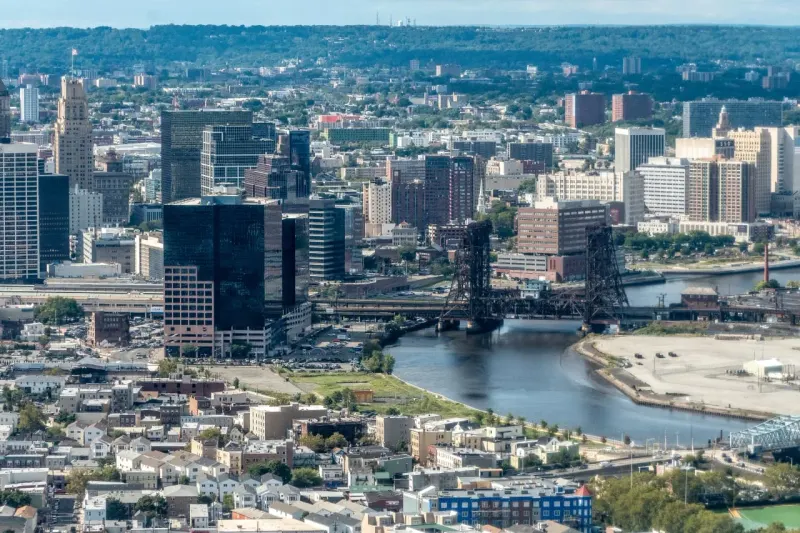 An inflated house-shaped U.S. map bulges in the Northeast above a needle, symbolizing widespread overvaluation.