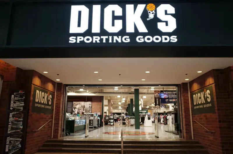 An unbranded sneaker sinks into discount tags, symbolizing weak sales and Dick’s record stock selloff.