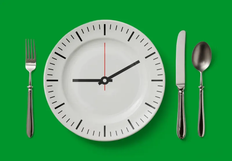 A plate-shaped hourglass resisted by a spring symbolizes fasting’s possible calorie cuts and required effort.