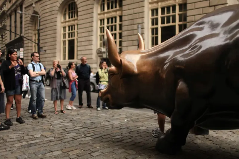 A bronze bull crosses a rising staircase bridge above a safety net, symbolizing stocks facing further Fed rate hikes.
