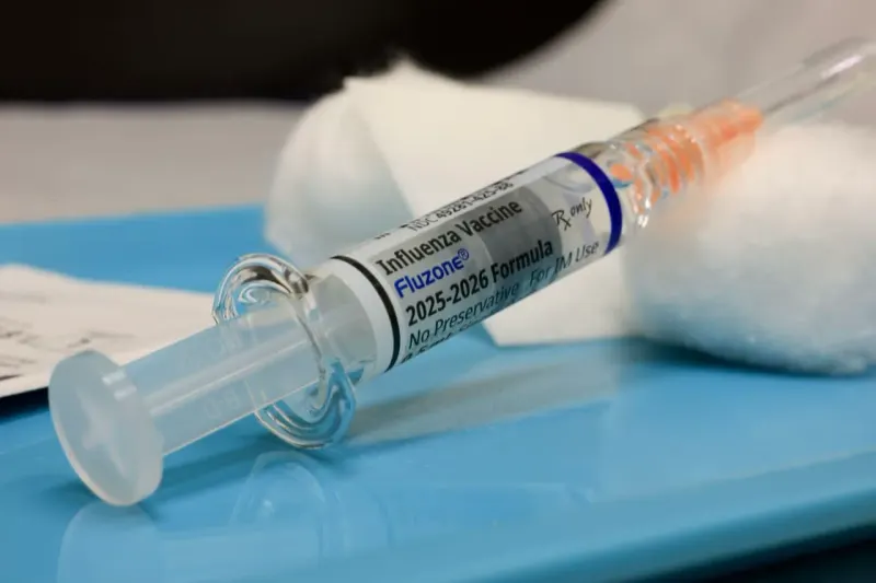 A syringe forms a clock hand racing seven calendar spaces ahead, symbolizing the unusually early flu season.