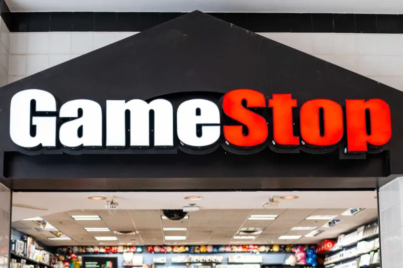 Collectible figures outweigh blank video game cases on a seesaw, reflecting GameStop’s changing revenue mix.