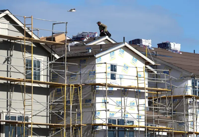 A new house is squeezed between rising coin stacks and a clipped price tag, symbolizing pressure on builders.