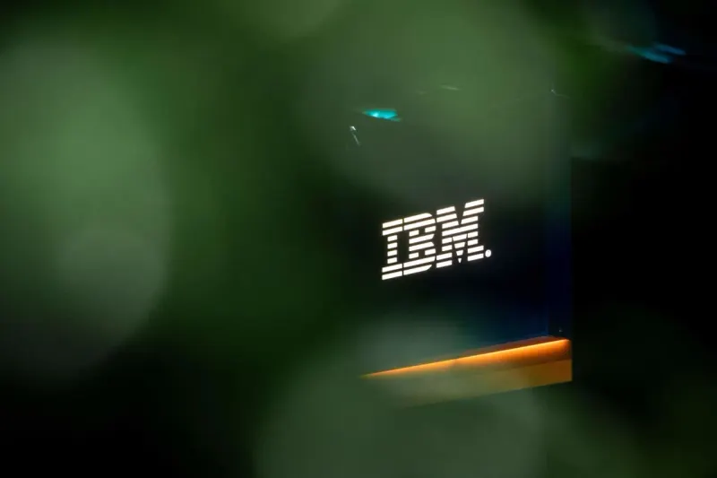 A blue cube balances on a descending platform, symbolizing IBM stock pressure after quarterly results.