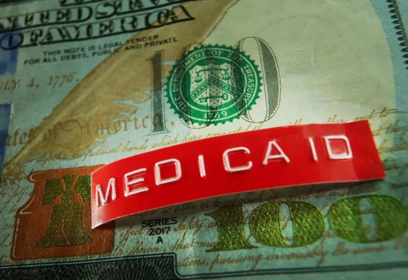 A giant time clock tears a medical safety net as coins pile up, symbolizing coverage losses and federal savings.