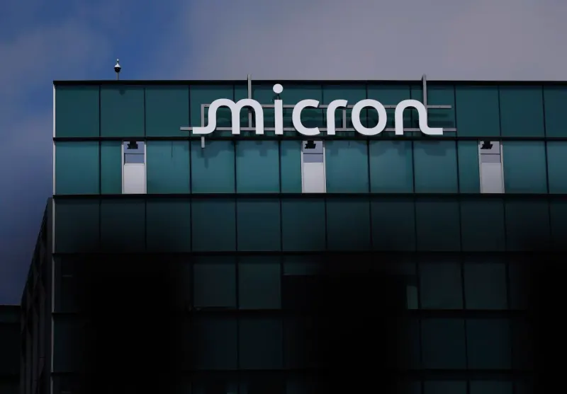 A memory chip balances on a shrinking pedestal as a red silicon tide rises, symbolizing Micron’s competitive pressure.
