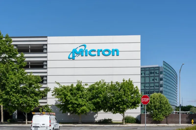 A semiconductor chip spring rebounds toward a heavy weight, symbolizing the memory market's pending test.