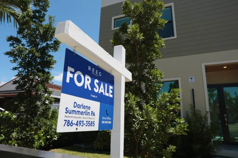 A paper house sinks beneath a wave of Treasury bonds, symbolizing rising yields and mortgage costs.
