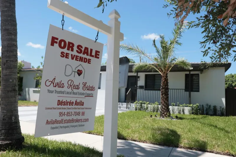 A small house strains on a sharply tilted, numberless rate dial, symbolizing high mortgage-rate pressure in 2027.