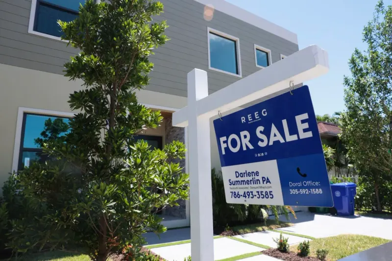 A house-shaped balloon pulled upward by an iron bond symbolizes rising mortgage rates during a bond selloff.