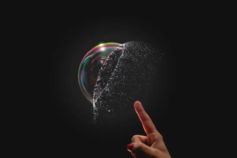 A cracked microchip-shaped bubble casts the shadow of an earlier burst bubble, linking the Nasdaq plunge to 2000.