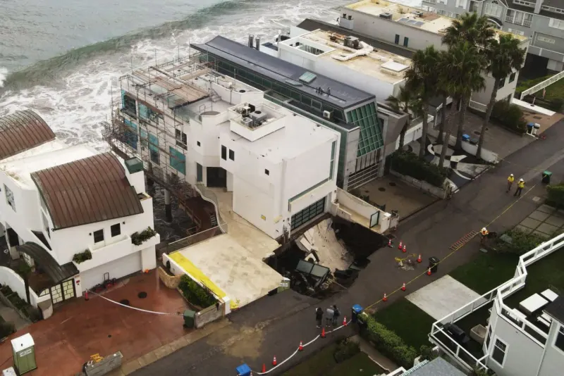 A luxury mansion balances above a void in a gold coin, symbolizing the sinkhole threat to Cage’s property.