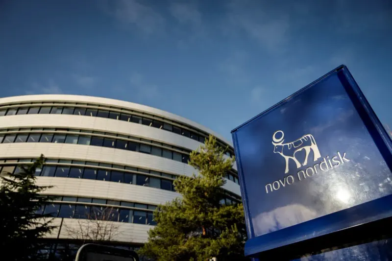 A stock certificate slides down an injection pen shaped as a steep ramp, symbolizing Novo Nordisk's 70% decline.