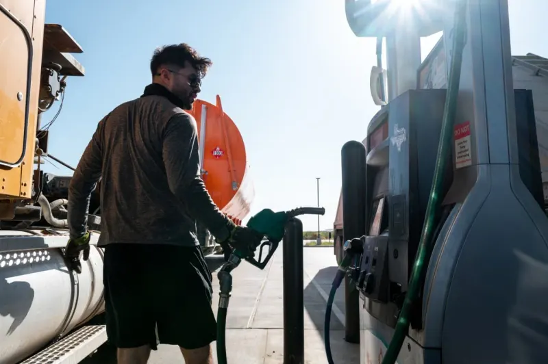 A grocery cart becomes a fuel gauge nearing the red zone, symbolizing fuel-driven pressure on household costs.