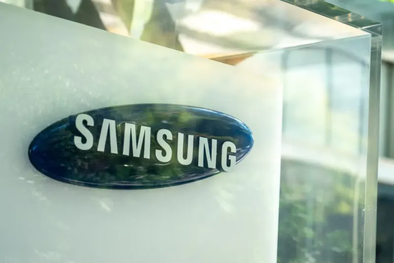 A giant memory chip nearly balances two silicon blocks, symbolizing Samsung's earnings comparison.