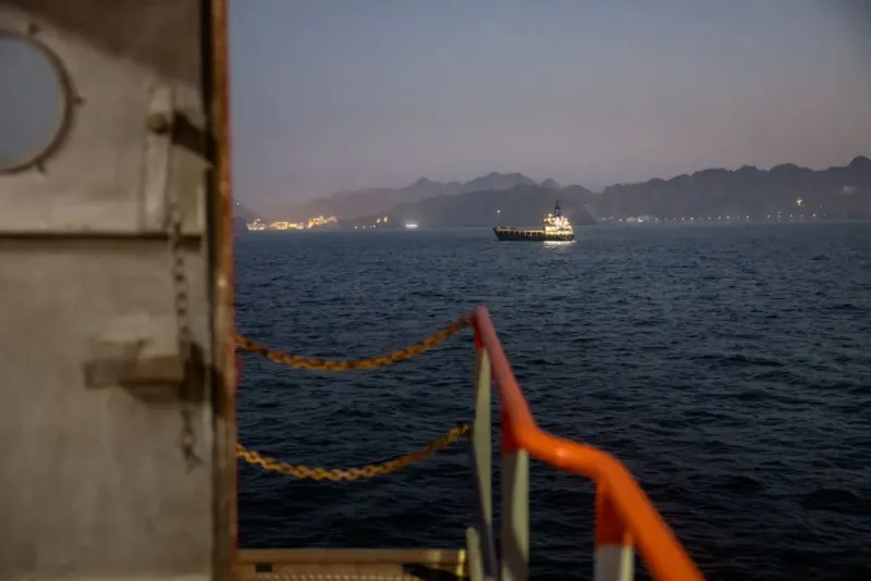 A blocked oil artery diverts a black stream through a narrow blue hourglass, reflecting Saudi Arabia's constrained export route.