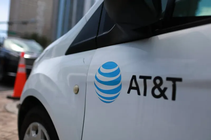 A satellite casts a falling-chart shadow over a cellular tower, symbolizing SpaceX pressure on AT&T stock.