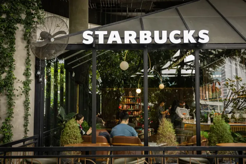 A coffee cup locomotive strains through syrup, symbolizing Starbucks' promising but slow turnaround.
