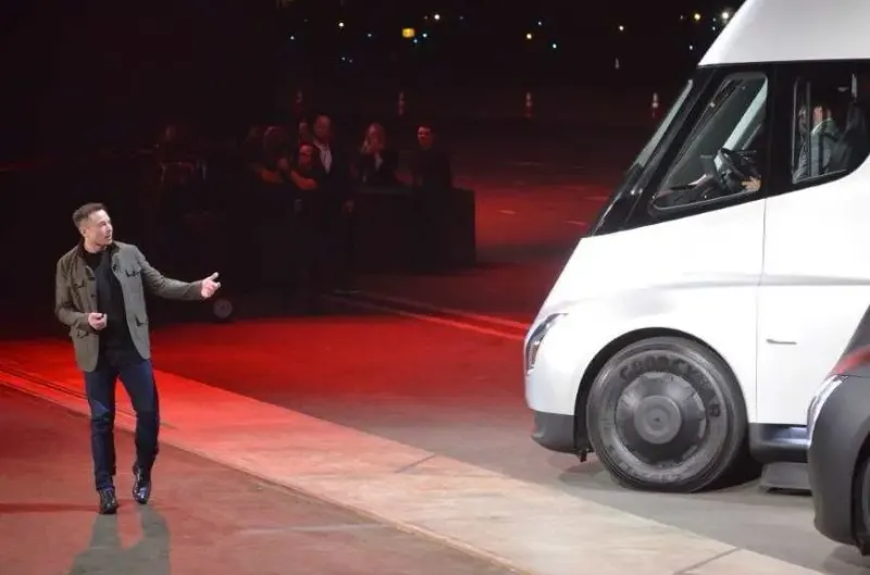 A burst of new machinery contrasts with a robotaxi wheel stuck in molasses, symbolizing Tesla's execution risk.