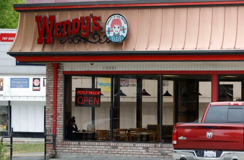A cracked hamburger-shaped piggy bank absorbs gold coins, symbolizing the costly capital needed to overhaul Wendy’s.