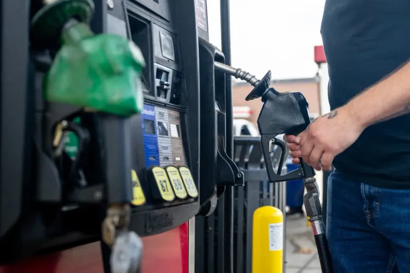 A golden oil barrel outweighs a cracked piggy bank, symbolizing energy fortunes against record consumer gas costs.