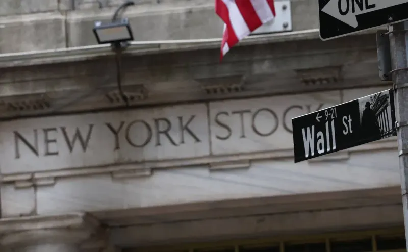 A rising interest-rate dial casts an oversized jagged shadow over a fragile market graph.