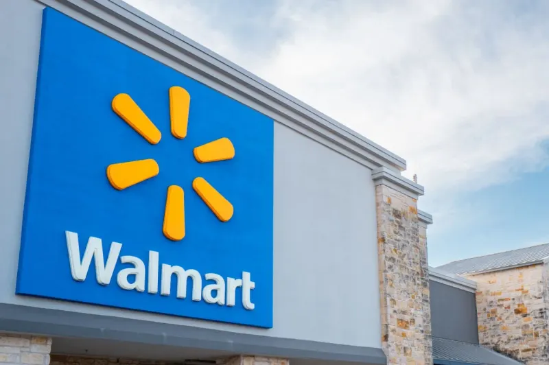 A shopping cart climbs a steep hill as its medicine-capsule wheel shrinks, symbolizing Walmart’s slowing sales growth.